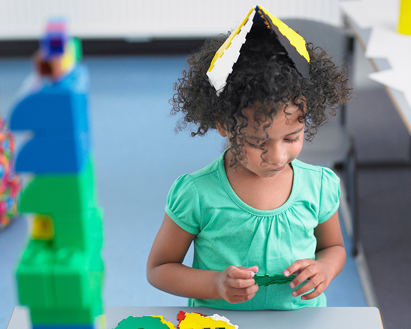 Young black girl in a green shirt playing with blocks during play therapy for children in Bel Air, MD