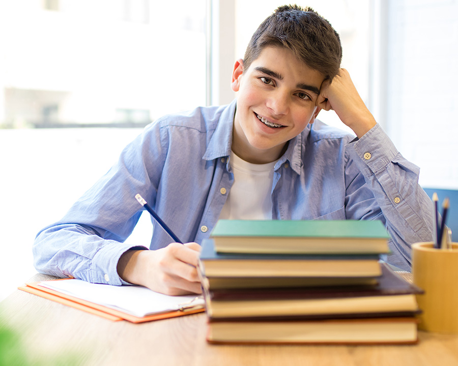 Teen boy with stack of books ready for therapy with Leah Brody